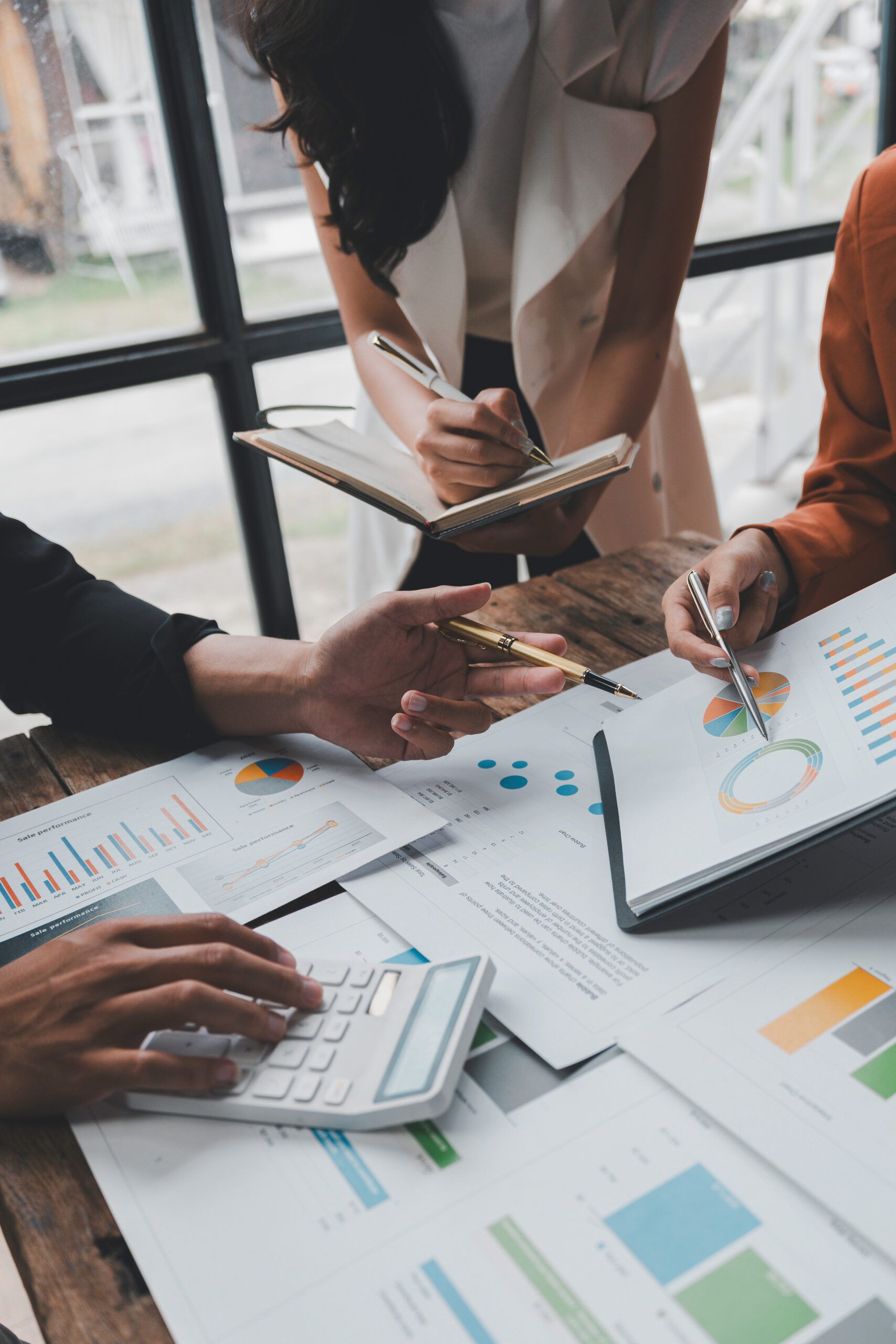 Business team analyzing financial reports using calculator and taking notes during a productive meeting